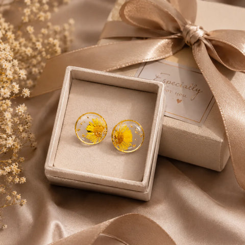Yellow daisy resin stud earrings with gold flakes displayed in a premium gift box setup with elegant ribbon and soft luxury background