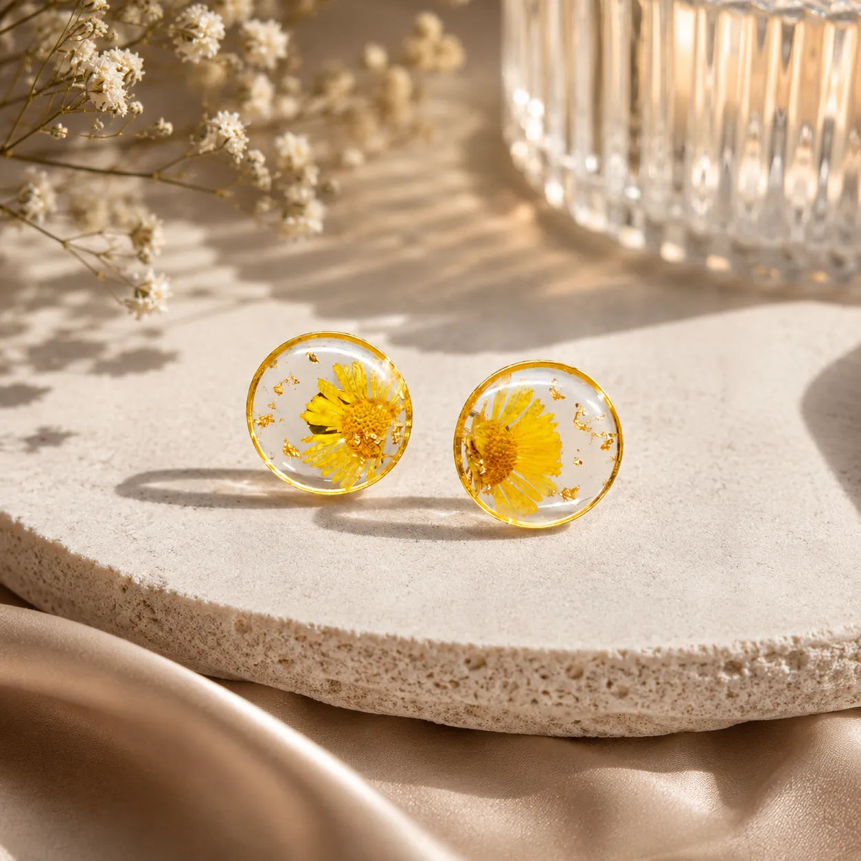Yellow flower earrings on a stone surface with a soft background